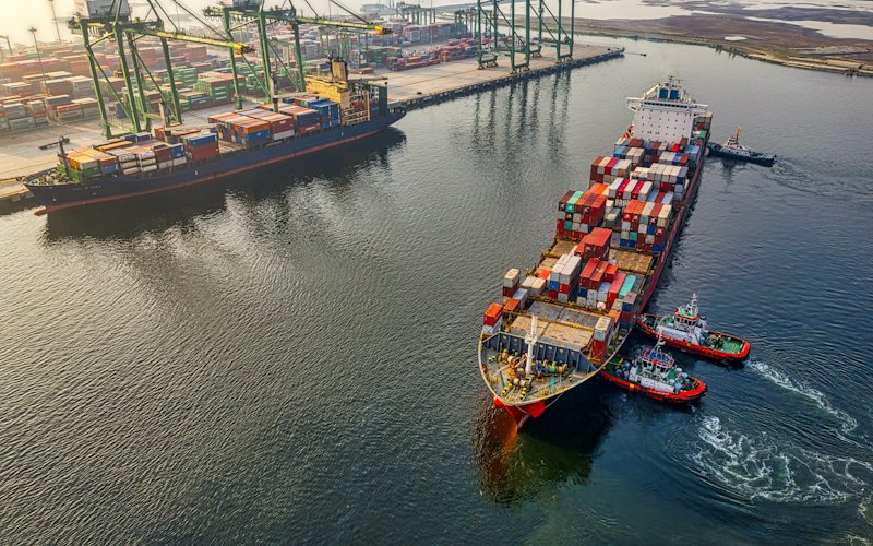 Tàu container cập cảng cạnh bãi container và cần cẩu