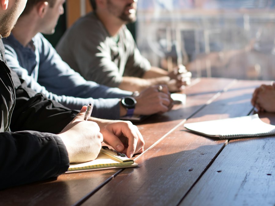 Nhóm làm việc ghi chép quanh bàn gỗ
