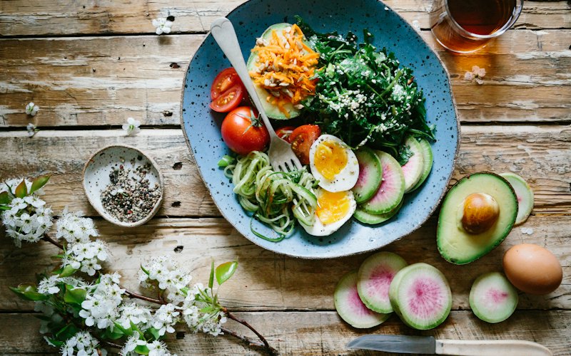 Đĩa salad rau củ, trứng và bơ trên bàn gỗ