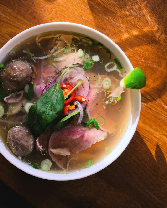 Tô phở bò với thịt tái, bò viên, rau thơm và chanh