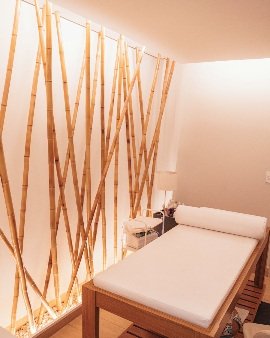 Phòng trị liệu ấm áp với vách tre và giường massage trắng