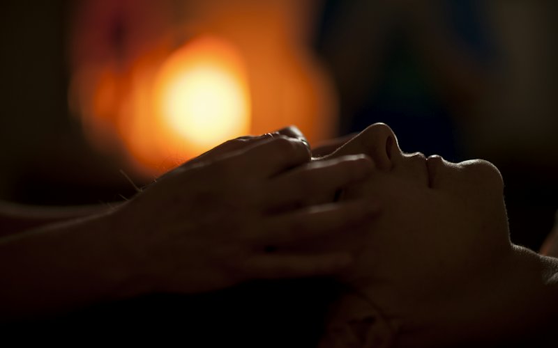 Đôi tay massage nhẹ vùng đầu dưới ánh đèn ấm