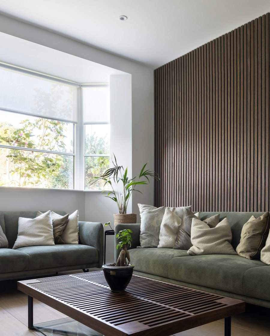 Phòng khách với tường lam gỗ và ghế sofa xanh rêu
