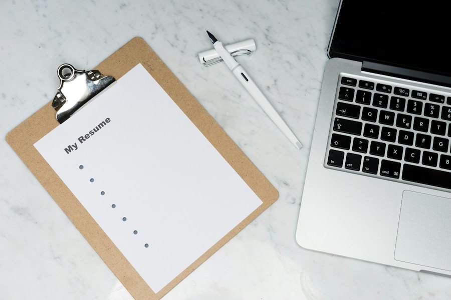 Bìa kẹp hồ sơ ghi My Resume đặt cạnh máy tính
